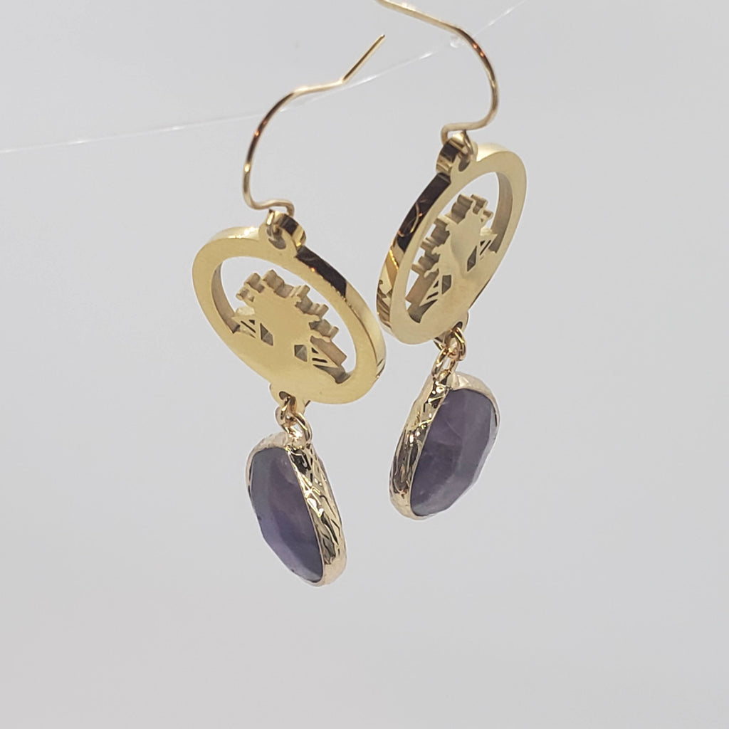 Our Amethyst Water Drop Earrings feature a natural stone, amethyst pendant, outlined in gold-tone, contrasting our signature lady Bantu, carved silhouette, plated in 18k gold, and topped off with a French hook.  Made for pierced ears.  Details:  Faceted natural amethyst stone  18K gold-plated  18k gold-plated French hook  1.8 inches drop  Wire-work finished in The San Francisco Bay Area